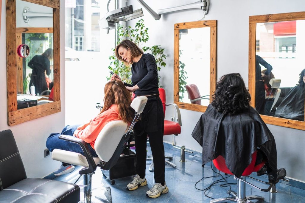 A hairdresser styles a client's hair in a salon.